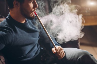 Büyük bir sigara içen genç yakışıklı adamdır