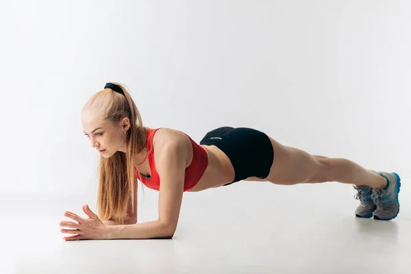 Hermosa deportista aprieta el núcleo, las empresas hasta su botín . — Foto de Stock