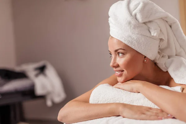 Gelukkig jonge vrouw liggend op een massagetafel in spa salon . — Stockfoto