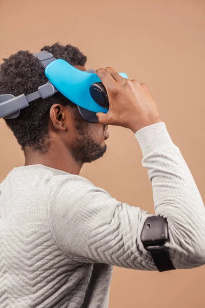 Black man wearing 3d vr glasses, playing videogame, holding joystick in hands