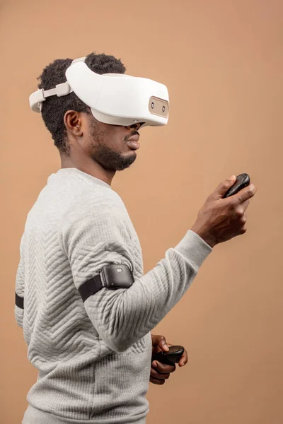 Black man wearing 3d vr glasses, playing videogame, holding joystick in hands