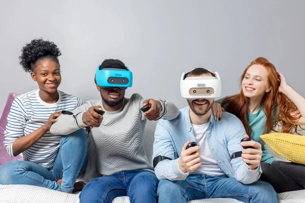 Dos chicos jugando videojuegos usando gafas VR y novias los apoyan . — Foto de Stock