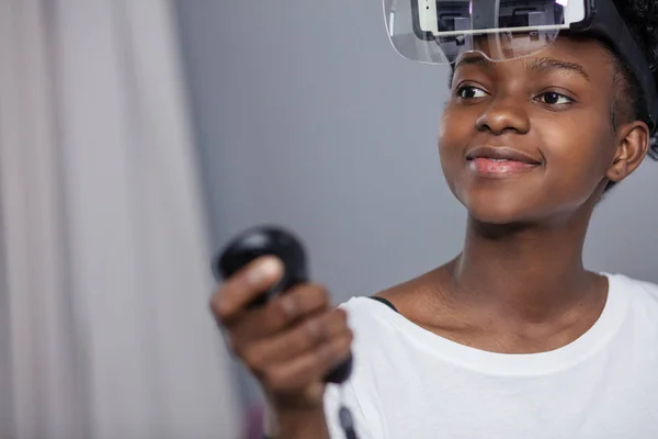 Mujer africana viendo vídeo usando gafas VR con control remoto en casa . —  Fotos de Stock