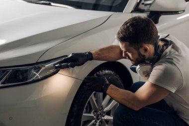 genç adam arabanın yakınında oturan ve onun boya sınama