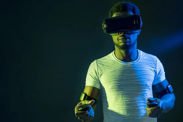 African Man in white, wearing VR Headset on green blue dual color background.