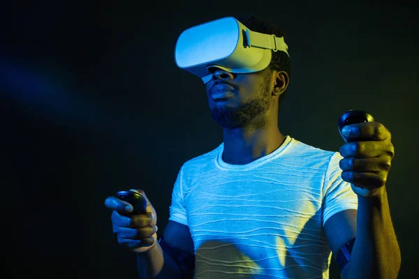 Uomo africano in bianco, indossando VR Headset su sfondo verde blu doppio colore . — Foto Stock