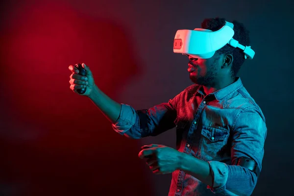 African Man in bianco, indossando VR Headset su sfondo rosso e blu doppio colore . — Foto Stock