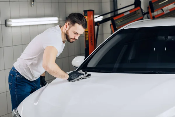 Serio uomo bello pulizia auto con panno in microfibra — Foto Stock