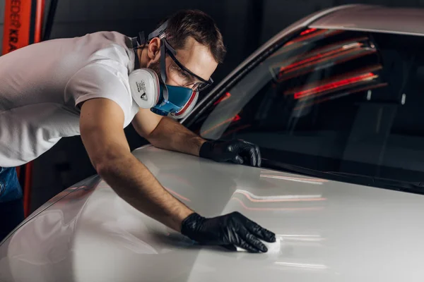 Mann hält Mikrofaser in der Hand und poliert sein weißes Auto. — Stockfoto
