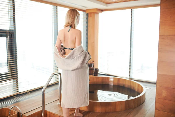Kobieta, relaks w pobliżu drewnianej beczce kąpiel przy lampce wina w ręku, obchody w koncepcji spa i sauny — Zdjęcie stockowe