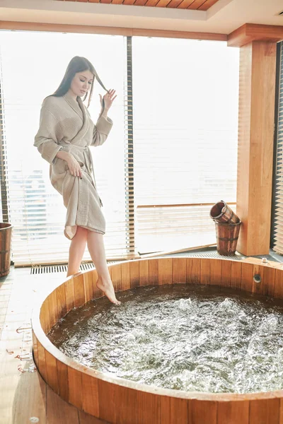 Brunetka kobieta relaksując się w jacuzzi w centrum spa z panoramicznymi oknami — Zdjęcie stockowe