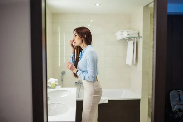 Vacker kvinna i formella slitage tittar på spegeln när du tvättar händerna i badrum — Stockfoto
