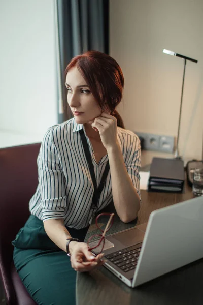 Masada oturan ve dizüstü bilgisayarda çalışan Kızıl saçlı kadın — Stok fotoğraf