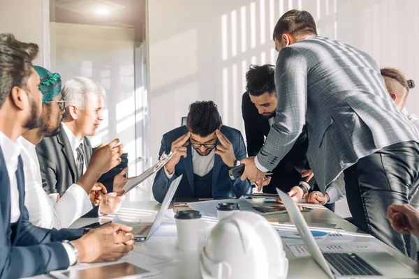 Young boss with colleagues looking at him during meeting at conference room