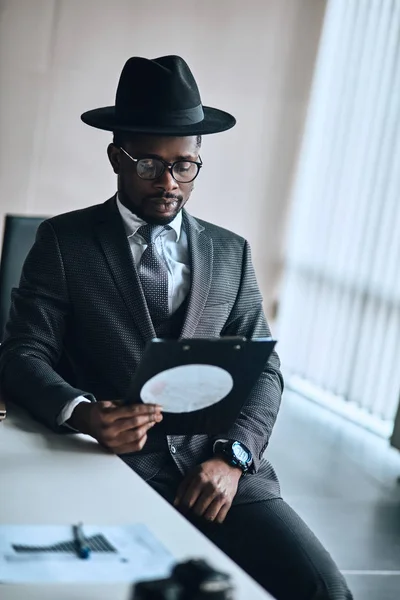 Hombre de negocios está sentado y mirando a través de documentos en la carpeta — Foto de Stock