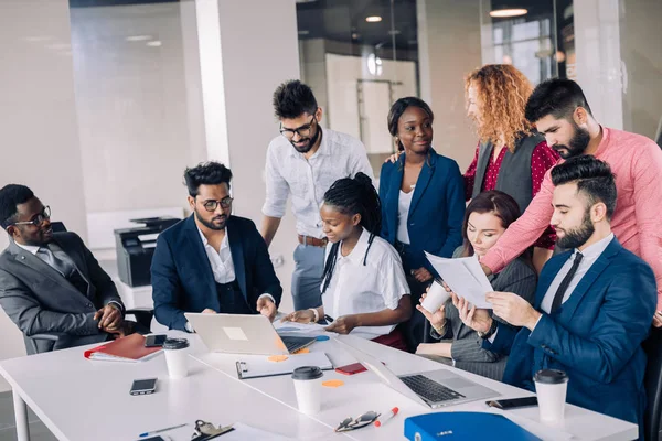 Junges multiethnisches Arbeitsteam tauscht Ideen rund um Laptop-Computer aus — Stockfoto