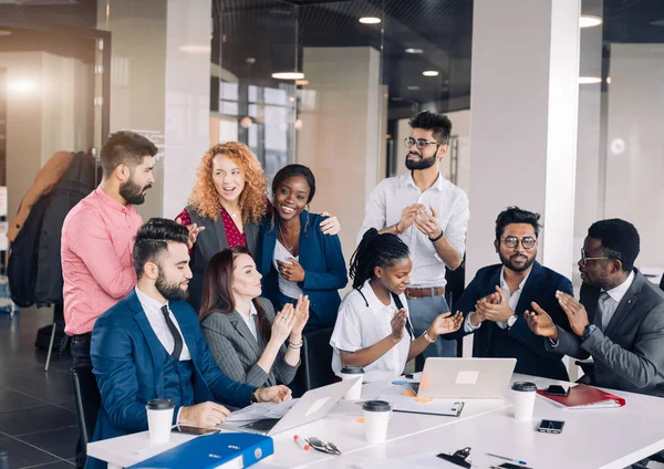 Jong multi-etnisch team wisselt ideeën uit rond laptopcomputers — Stockfoto