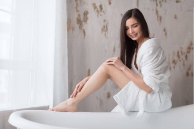 Beyaz cüppeli Spa Avrupalı kız, banyoya hazırlanıyor, suya bakıyor.