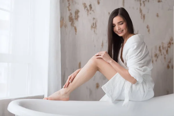Spa europees meisje in witte badjas, voor te bereiden om te baden, op zoek naar water — Stockfoto