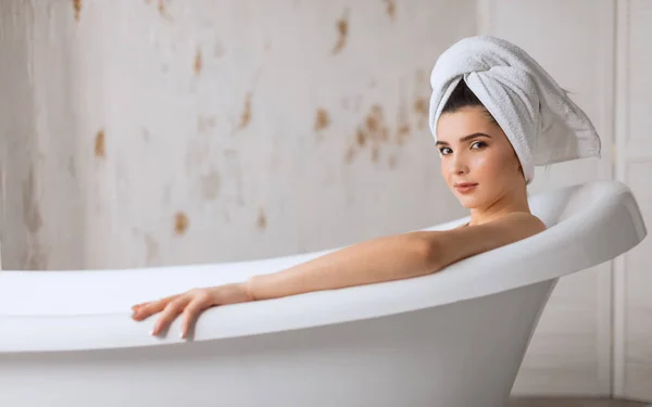 Avslappnad ung kvinna ligger i badkar — Stockfoto