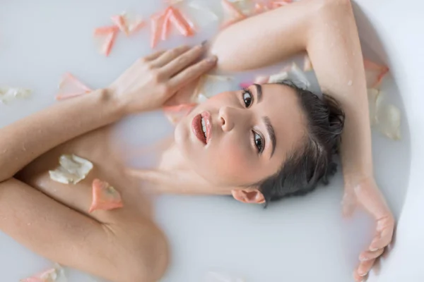 꽃잎으로 젖 냄새 목욕을 하는 젊은 여자 — 스톡 사진