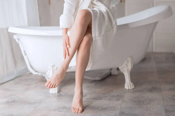 Fiatal nő részben öltözött köntös, ügyelve a lábát fürdés után — Stock Fotó