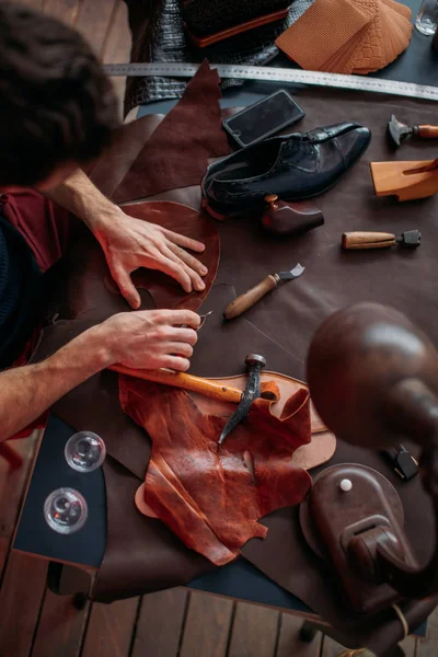 Messy shoemakers mesa, homem concentrado em consertar sapatos — Fotografia de Stock