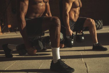 İki çok ırklı erkek sporcular ile ağırlık lunges kapalı egzersiz yapma