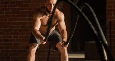 Genç Beyaz adam birlikte savaş ipler bir spor salonunda egzersiz