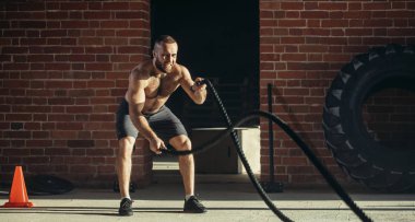 Genç Beyaz adam birlikte savaş ipler bir spor salonunda egzersiz