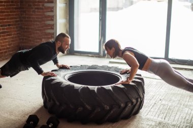 Kişisel antrenör yardımı ile kamyon lastiği ile çalışma dışarı genç eğitimli kadın
