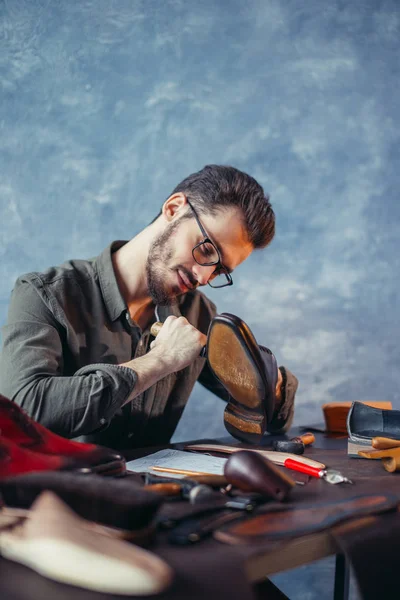 Hardworking guy peel off the sole of leather footwear — Stock Photo, Image