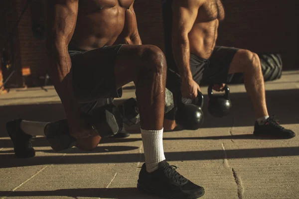 Två raser manliga idrottare att göra utfall med vikt i inomhus träning — Stockfoto
