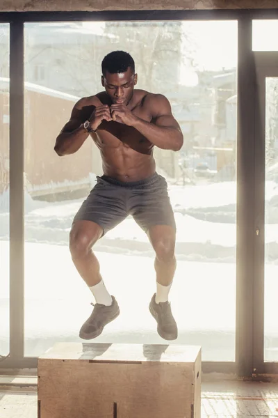 Afrikaanse sterke man uitvoeren plyo vak sprong oefening tijdens crossfit training — Stockfoto