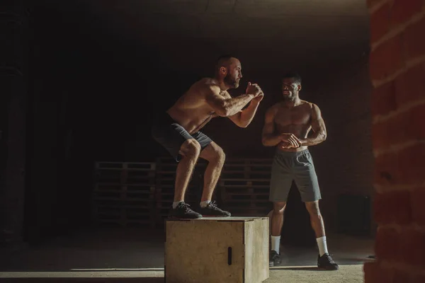 Musculosos amigos atléticos multiétnicos haciendo saltos de caja mientras hacen ejercicio en el gimnasio —  Fotos de Stock