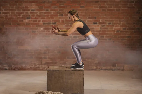 Side view image of fit young woman doing a box jump exercise.