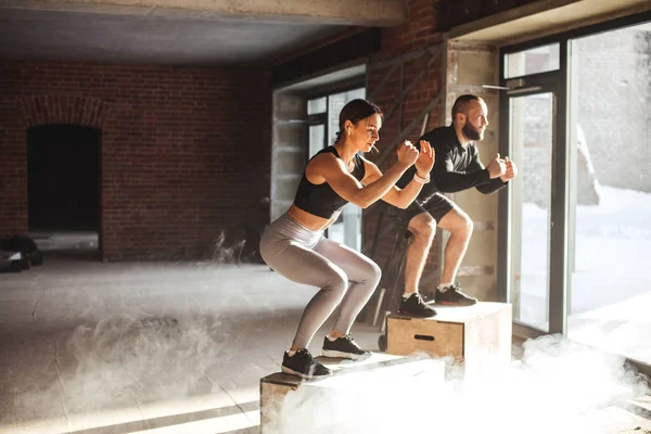 Hombre y mujer saltando tohether en cajas en el gimnasio, entrenamiento funcrional para las personas — Foto de Stock