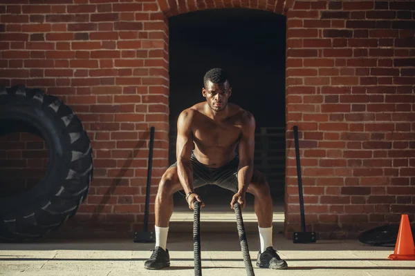 Ung afrikansk man tränar med slaget rep på ett gym — Stockfoto