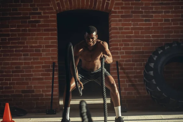 Afrikaanse jongeman uit te werken met touwen van de slag bij een sportschool — Stockfoto