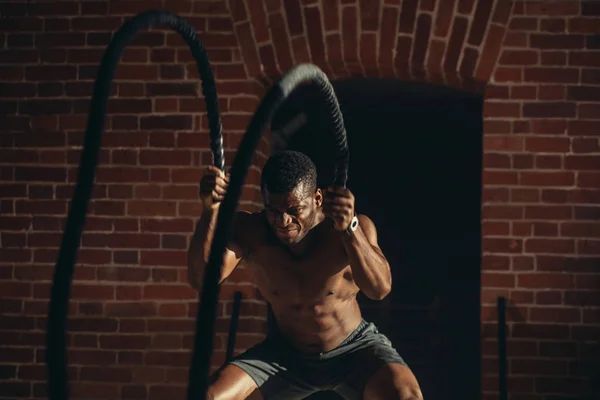 Ung afrikansk man tränar med slaget rep på ett gym — Stockfoto