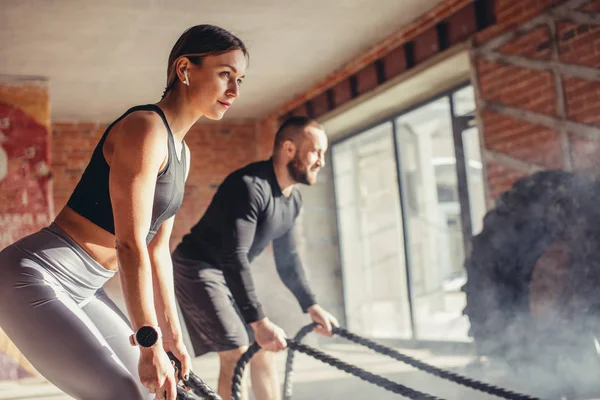 Mulher e homem no ginásio treinamento funcional com exercício de corda de batalha — Fotografia de Stock