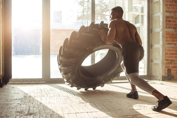 Atletisk afroamerikanska man tränar med däck och tittar bort i gymmet — Stockfoto