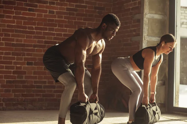 Karışık yarış çift ağız kavgası yaparken egzersiz, ağır kum torbalarının elinde tutarken.