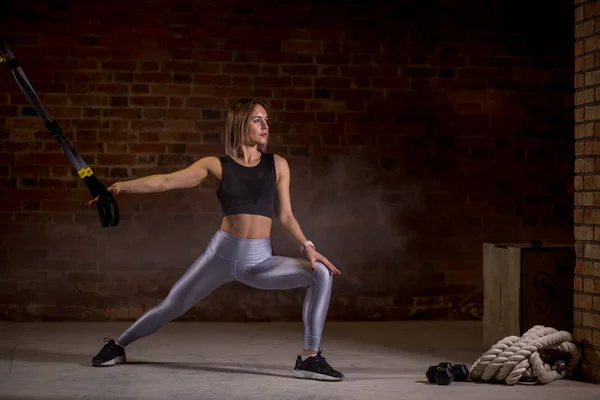 健身的女士在健身房的 trx 肩带上锻炼。交叉贴合风格。培训技术. — 图库照片