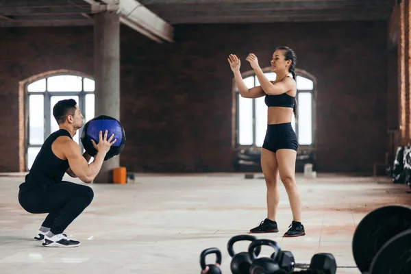 Sportos férfi és nő dobtak egy fitness labda egymással a sportközpont — Stock Fotó
