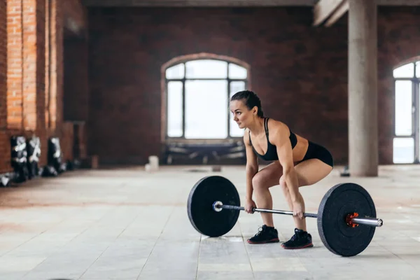 De foto van de volledige lengte van kant weergeven van rslim sterk meisje uit te werken met een barbell — Stockfoto