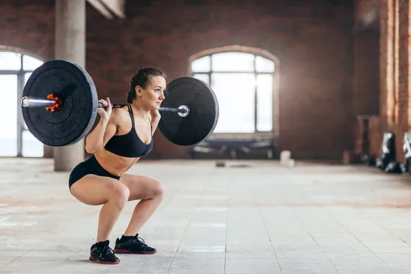 Robustní výkonný holka dělá squatu s těžkou činku — Stock fotografie