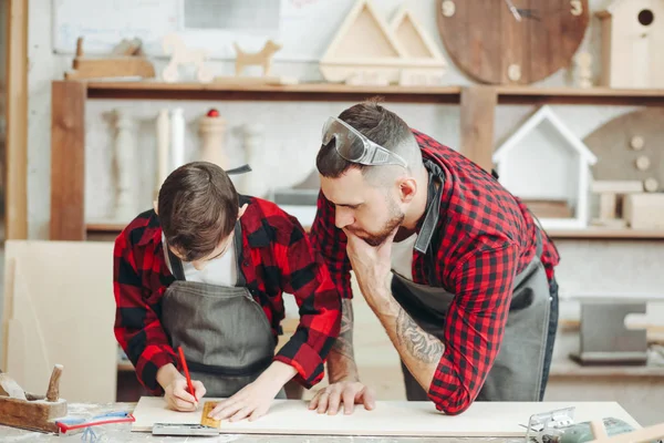 Hombres con regla y lápiz que miden tablón de madera para trabajar — Foto de Stock