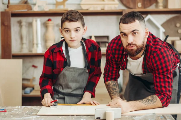 Baba ve oğul atölyede ahşap bir uçağın modelini tasarlıyorlar.