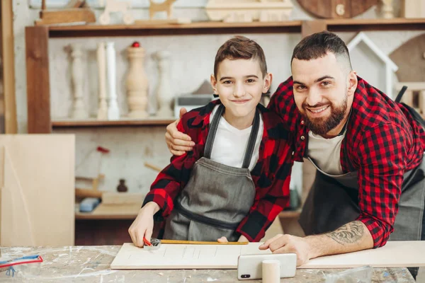 Papá e hijo en el taller jugando a diseñar un modelo de un plano de madera —  Fotos de Stock